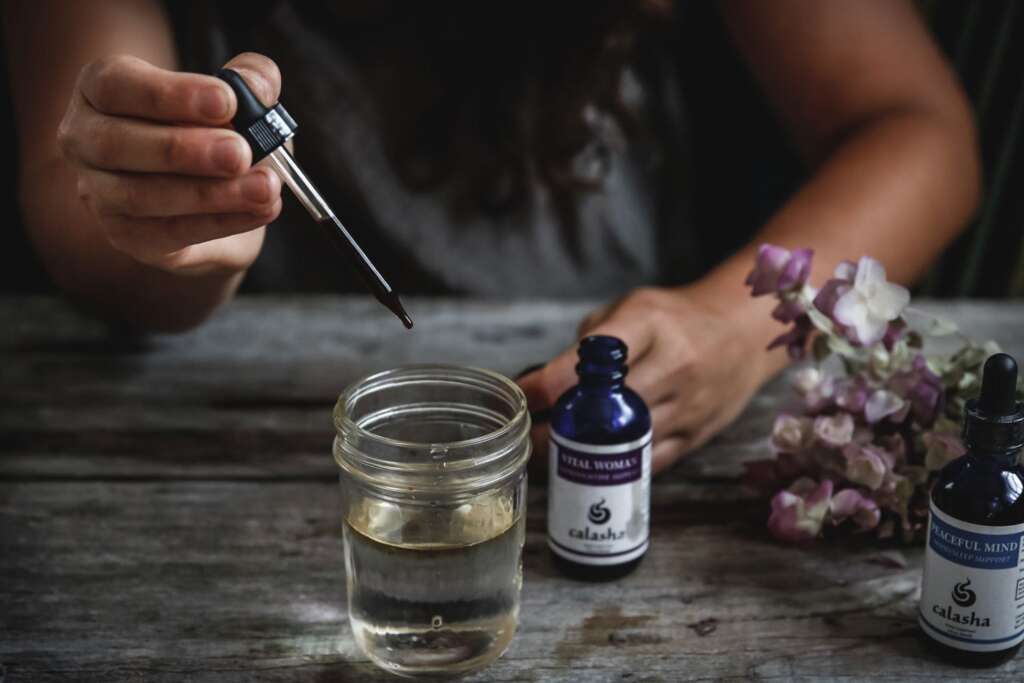 Image of person with eyedropper and herbal tinctures