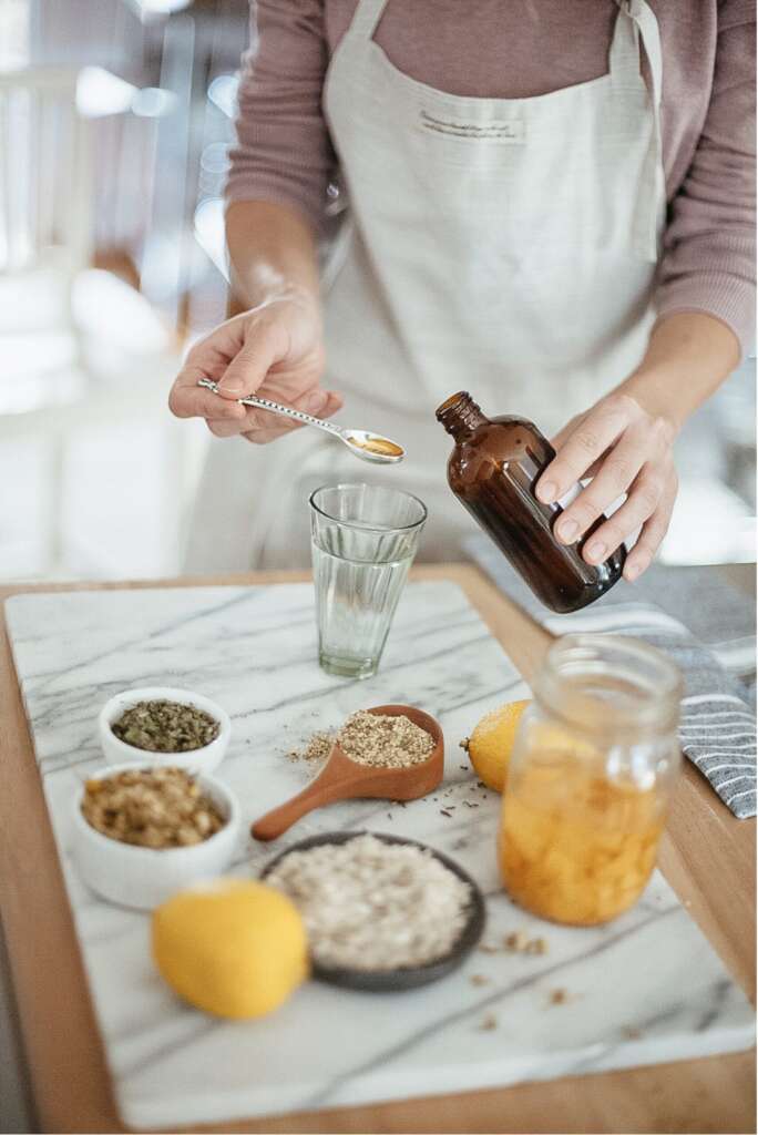 Woman standing over table mixing herbs and tinctures